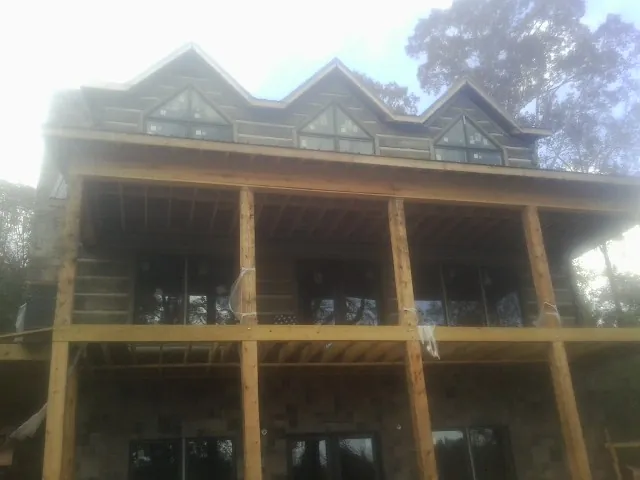Dormers and porch framing on a large log home under construction — Roof Coating work by our crew in Rochester